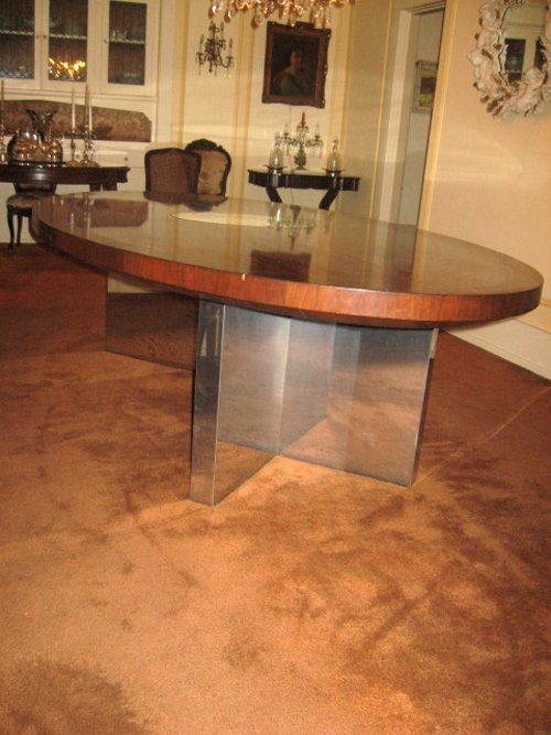 Dunbar Dining or Conference Table Mid to late 70s Designed by Roger Lee Sprunger, a protege of Edward Wormley An iconic piece wth high mirrored pristine finish of Brazilian Rosewood with Mahogany banned edges.  Polished Chrome Planks â€“ Plinths V shaped bases and middle secret drawer with Brass Dunbar tag.  Oval in shape and measuring 110 in. x 60 in.     - Extraordinary Auction - Nike Spillson Home Interiors & Furnishings
